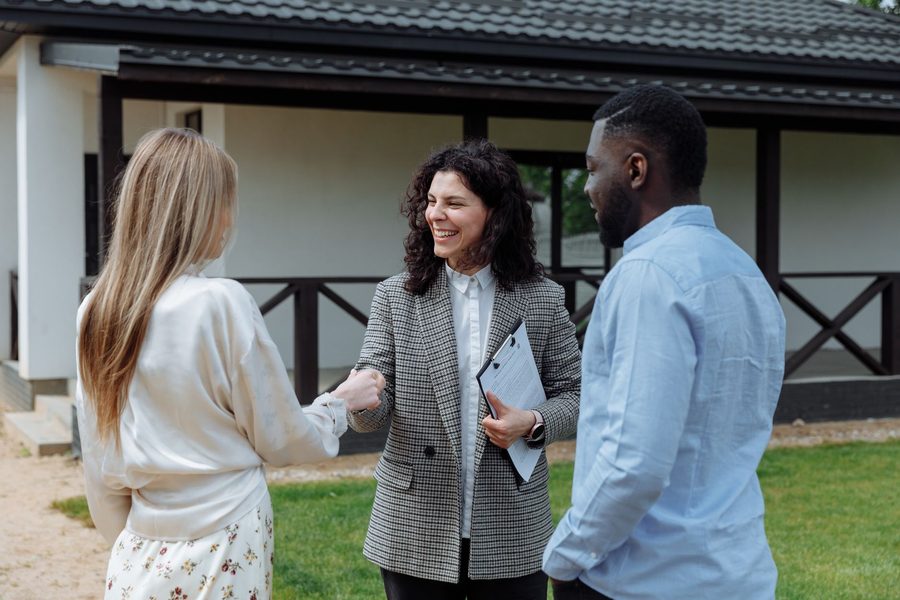 Two people shaking hands outside a house